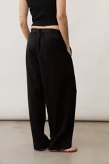 Pantalón de corte ancho y holgado, de color negro, con diseño estructurado y cinturón ajustable integrado en la cintura.