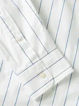 Camisa de manga larga de Tommy Hilfiger, color blanco con finas rayas verticales celestes, corte amplio, cuello clásico, cierre frontal con botones, un bolsillo de parche en el pecho con el logo bordado y puños abotonados.