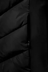 Cazadora de mujer con diseño híbrido, presenta un panel frontal acolchado con costuras en chevron y mangas y laterales en tejido liso. Cuenta con cuello alto, capucha ajustable con cordones elásticos y cierre frontal mediante cremallera.