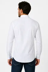 Camisa de algodón a rayas verticales azules y blancas, de manga larga, con cuello camisero y cierre frontal con botones.