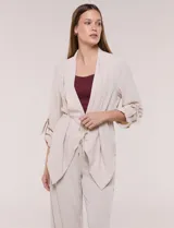 Chaqueta liviana color beige de silueta fluida y diseño abierto, con solapa caída, cintura con cordón ajustable y mangas 3/4 con presilla y argolla metálica.