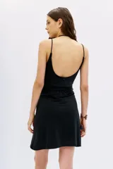 Vestido corto negro ajustado al cuerpo, con escote cruzado en V, breteles finos y lazo ajustable en la cintura.