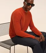 Sueter de punto liviano para hombre, de color naranja con textura acanalada horizontal, cuello redondo y mangas largas con puños ajustados.