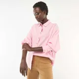 Camisa de corte holgado y diseño oversize en color rosa, con cuello clásico, mangas largas con puños abotonados y cierre frontal con botones de efecto concha.