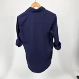 Camisa azul marino de algodón con cuello italiano, manga larga con puños abotonados y cierre frontal con botones blancos. Tiene un logo bordado en blanco en el pecho.