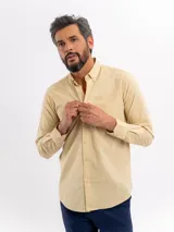 Camisa de manga larga color beige con efecto lino, de corte clásico con cuello camisero, botonadura frontal y un bolsillo aplicado en el pecho.