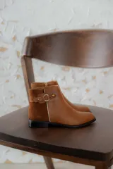 Botas cortas de cuero negro con paneles traseros de gamuza, cierre lateral y detalle de correa con hebilla metálica en el tobillo.