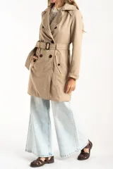 Trench impermeable de corte oversize en color camel, con diseño de doble botonadura, solapas clásicas y cinturón ajustable en la cintura.
