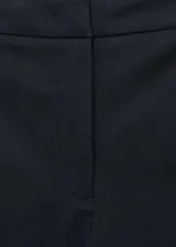 Pantalón de vestir azul marino de corte ajustado y tobillero, con bolsillos laterales, trabillas para cinturón y cierre frontal con cremallera y botón oculto. Presenta pequeñas aberturas en los bajos.