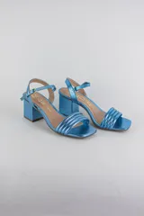Sandalias de fiesta metalizadas color celeste, con taco cuadrado de 4 cm, tiras delanteras acolchadas y tira ajustable al tobillo con hebilla dorada.
