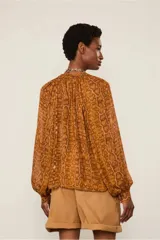 Camisa de mangas largas y amplias con estampado animal print, cierre de botones frontal y cuello padre con detalle fruncido.