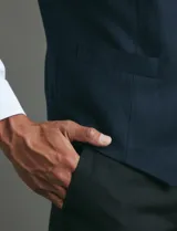 Chaleco de vestir color azul oscuro con textura sutil, corte clásico, cierre frontal con botones y bolsillos laterales simulados.