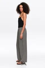 Pantalón de corte recto y tiro medio, con estampa de cuadros en blanco y negro. Posee cintura elástica y detalles de lazos ajustables en los tobillos.