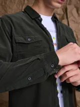 Camisa de pana color azul marino, con mangas largas, cuello clásico y dos bolsillos frontales con solapa y botón.