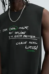 Camiseta sin mangas (tank top) negra, corte boxy fit, con cuello redondo y sisa con acabado irregular. Presenta un estampado frontal con texto manuscrito en verde y blanco que dice: "I look cool online, but offline I'm even better... Chase real likes!".