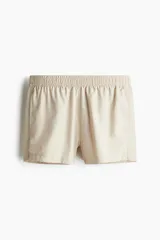 Short de baño color beige con cintura elástica y cordón de ajuste oculto. Presenta bolsillos laterales, aberturas laterales en el ruedo y suspensor interior de malla.