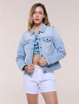 Camperita de denim clásico con lavado claro, cuello camisero, cartera frontal con botones metálicos y bolsillos superiores con solapa. Presenta mangas largas con puños abotonados y costuras estructuradas.