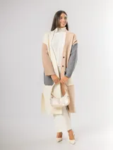 Sacón tipo tapado de corte largo, confeccionado en tejido de punto con diseño color block en tonos gris, negro y blanco. Presenta cierre frontal con botones, bolsillos laterales de parche y aberturas en los costados.