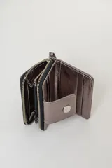 Billetera de cuero con textura tipo cocodrilo, color marrón, con cierre perimetral y solapa frontal con broche a presión metálico. Incluye una correa de muñeca desmontable.