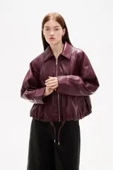 Campera de eco-cuero en color bordó, con cuello camisero, cierre frontal con cremallera y cordones ajustables en el ruedo.