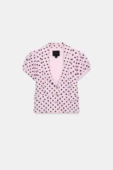 Chaqueta corta rosa con estampado de lunares negros, de cuello solapa y manga corta abullonada. Cuenta con falsos bolsillos con solapa en el delantero y cierre frontal con botones.