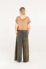 Pantalón palazzo de denim con doble pinza, tiro alto y pierna extra ancha con ruedo deshilachado. Presenta un efecto de teñido degradé irregular en tonos verde militar y marrón, cierre con botón y bolsillos laterales.