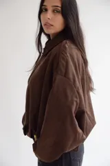 Campera tipo bomber de gamuza sintética color marrón, con cuello camisero, cierre frontal y diseño de corte holgado.