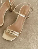 Sandalias de tacón bajo color blanco, con tiras finas y cierre con hebilla.