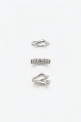 Set de tres anillos metálicos plateados con diseños irregulares y formas orgánicas.