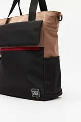 Cartera tote negra con doble asa superior y correa desmontable y regulable. Cuenta con un bolsillo frontal con solapa y cierre, y bolsillos laterales. Presenta pespuntes blancos decorativos y un logo cuadrado en la parte inferior.