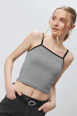 Top ajustado al cuerpo con estampado a cuadros blancos y negros, breteles finos y ribete negro en escote y sisas.