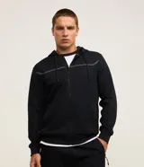 Campera deportiva de textura gofrada en color negro, con capucha, cierre frontal por cremallera y detalle de franja reflectante en el pecho.