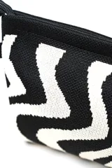 Neceser de diseño texturizado en tono beige, con cierre superior y una práctica tira de mano trenzada en blanco y negro con detalles oscuros.