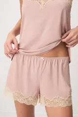 Pijama de dos piezas color verde menta, confeccionado en poliamida y elastano. Incluye una musculosa con tirantes finos y detalles de encaje beige en el escote, y un short con cintura elástica, pequeño lazo decorativo y apliques de encaje en los ruedos.