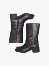 Botas de media caña de cuero sintético en color marrón oscuro con efecto avejentado, tacón ancho y suela flatform. Cuentan con cierre lateral interno y tiras decorativas con hebilla metálica y argolla en el tobillo.