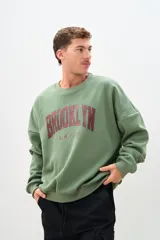 Buzo verde oliva con estampa en el frente con la palabra "Brooklyn" en color bordó y la frase "New York" en color gris.