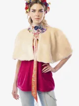 Capa corta de piel sintética en color beige, con diseño reversible que incluye un forro de satén con estampado floral. Presenta un lazo frontal estampado con borlas decoradas con cristales.