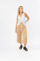 Pantalón de corte culotte y tiro medio, confeccionado en viscosa con estampado de hojas blancas sobre fondo color miel. Presenta una silueta amplia y fluida, con cintura elástica en la parte posterior y bolsillos laterales.