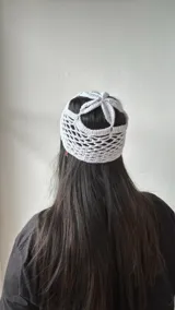 Gorro blanco de crochet con diseño de red y aberturas en la parte superior.