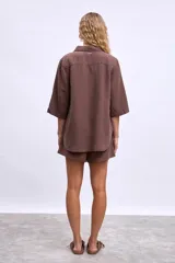 Camisa marrón de manga 3/4, con cuello clásico, botones frontales y un bolsillo en el pecho.