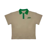 Remera tipo polo color beige de algodón grueso con cuello verde y bordado verde en el pecho.