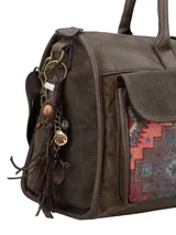 Cartera tipo bolso de mano y bandolera en color marrón, con diseño patchwork étnico en los bolsillos frontales. Cuenta con dos bolsillos exteriores con solapa y broche magnético, cierre principal con cremallera, manijas fijas y correa ajustable y removible. Incluye un llavero decorativo con borlas y dijes colgantes en el lateral.