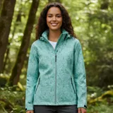Campera cortaviento impermeable y transpirable de la marca United Uy. Presenta un diseño estampado con motivos de hojas en tonos verdes, cierre frontal completo, capucha ajustable y bolsillos laterales con cierre. Es una prenda ultraliviana ideal para actividades al aire libre.