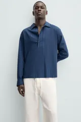 Camisa polo de manga larga con cierre frontal de botones, confeccionada en tejido con textura de rayas verticales sutiles.