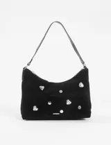 Bandolera negra de cuero vegano, estilo vintage, con tachas plateadas en forma de corazón y hexagonales, y apliques de strass. Tiene una correa de hombro ajustable y cierre de cremallera.