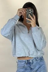 Buzo deportivo color blanco con cuello polo y cierre frontal parcial. Presenta mangas largas con puños elásticos y ruedo ajustable con cordón elástico.