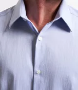 Camisa de vestir blanca de algodón con textura maquinetada, cuello camisero y mangas largas.