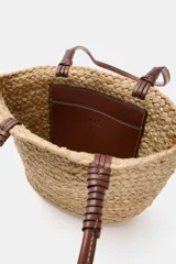 Bolso tipo shopper formato mini confeccionado en yute trenzado, con doble asa de mano en cuero sintético color marrón.
