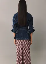 Chaqueta vaquera azul con cuello camisero, cierre frontal con botones metálicos, tres bolsillos delanteros, mangas largas con puños abotonados y cinturón de lazo.
