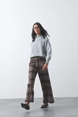 Polera de tejido de punto color gris, con cuello alto, mangas largas abullonadas con puños elásticos y costura central vertical en el frente. Presenta una abertura sutil en la espalda.